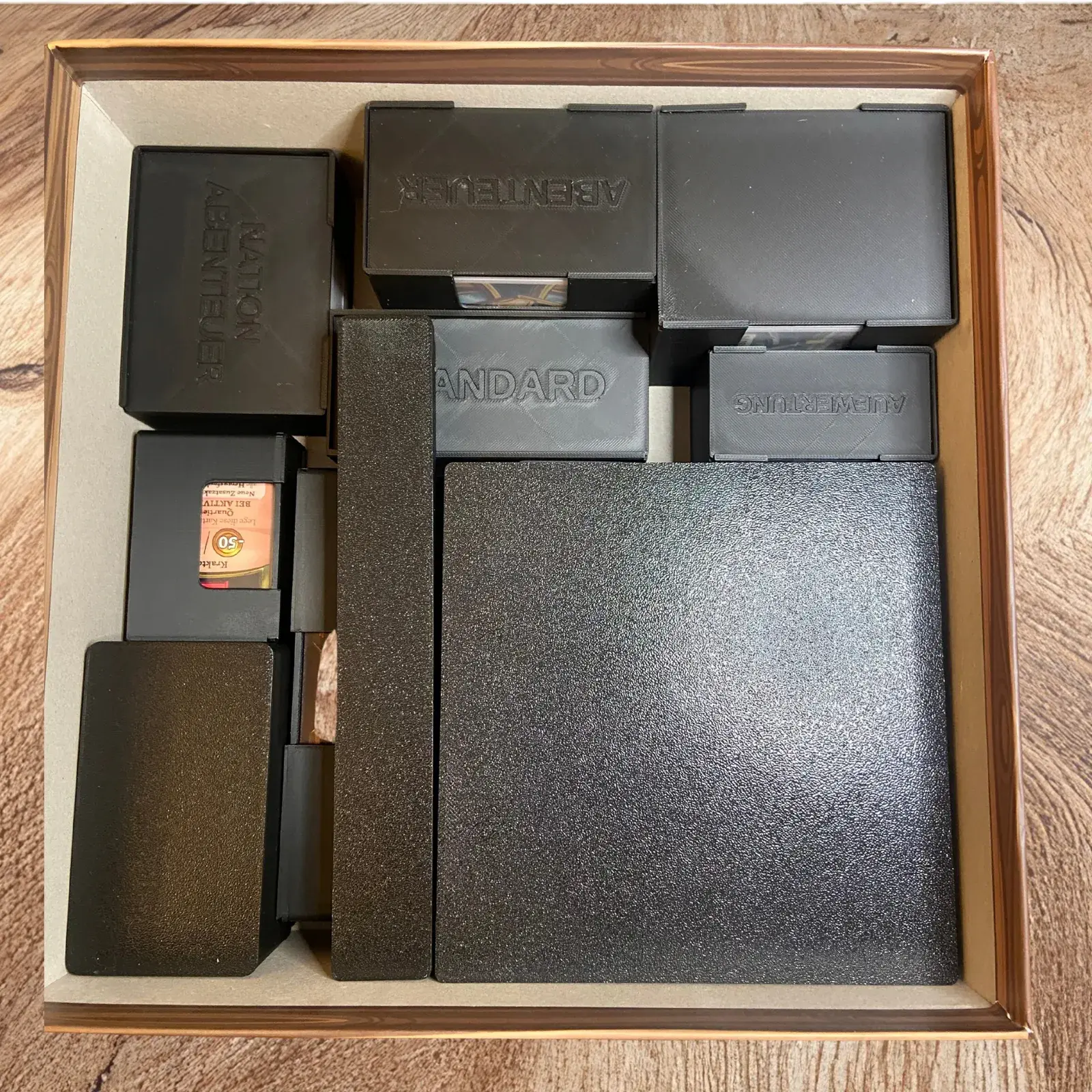 Spielkarton von oben mit den schwarzen Inlay-Boxen eingeräumt, kompatibel mit EOS
